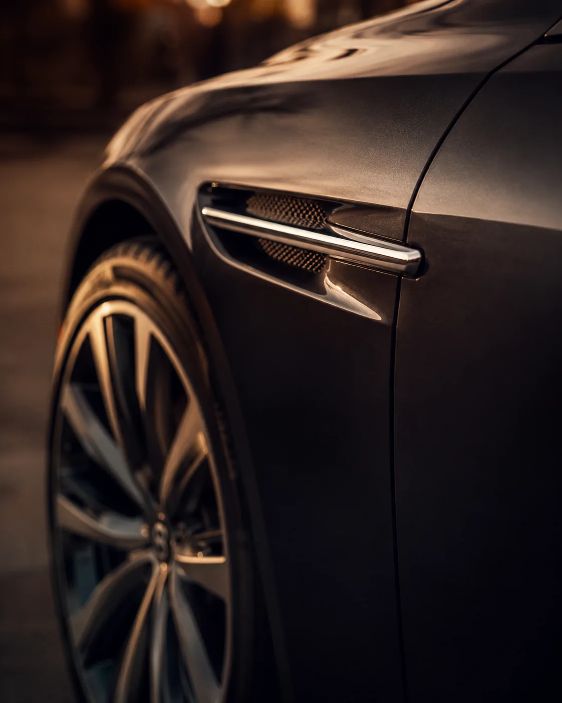 Detail of a prestige performance car, wing vent and alloy wheel in warm low light