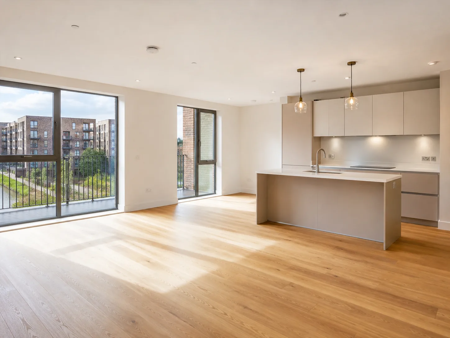 The interior of a finished new-build British apartment with oak flooring and a plain kitchen